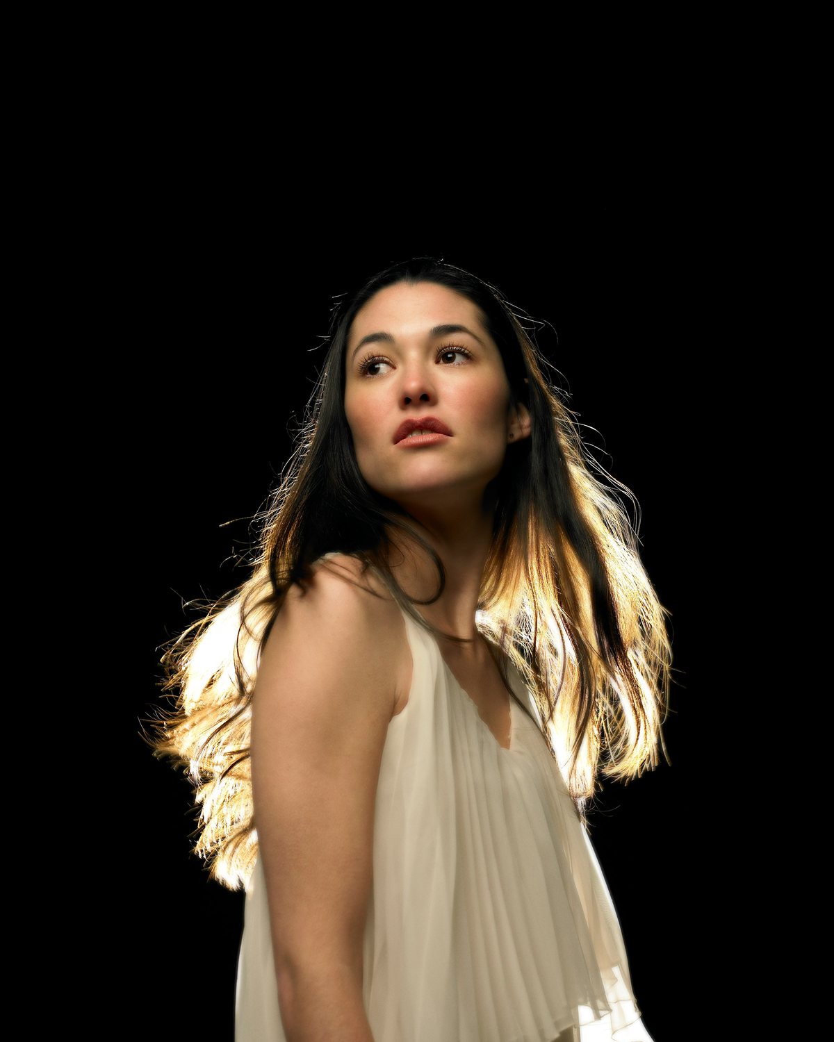 Portrait lit with rim lighting from behind, with a bright edge along the hair and shoulders